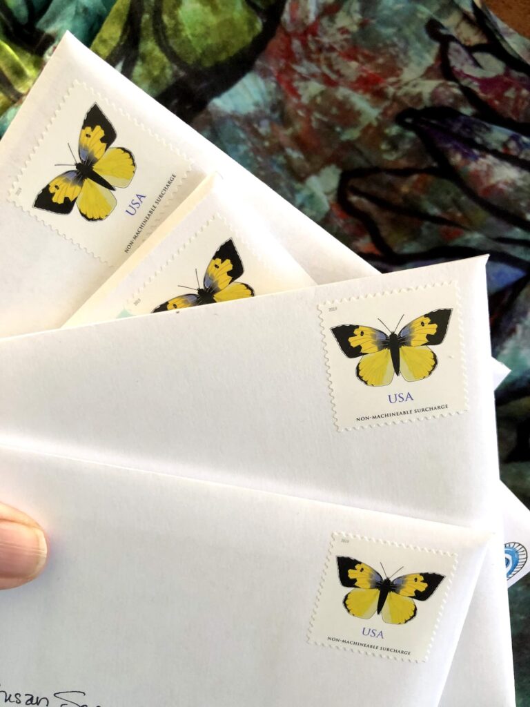 a stack of envelopes fanned out with a butterfly stamp on them