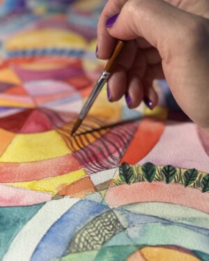 actively painting a watercolor painting. It has circles of colors, a paintbrush and hand in the image
